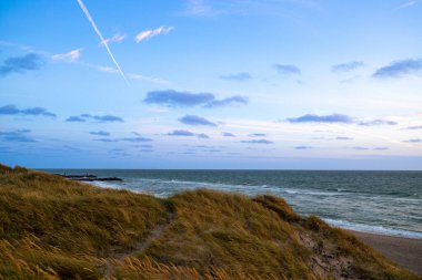Kum tepeleri arasında Danimarka sahilinden Kuzey Denizi 'ne gün batımı. Yüksek kalite fotoğraf