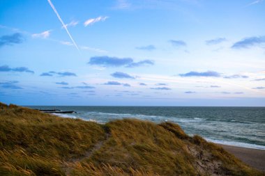 Kum tepeleri arasında Danimarka sahilinden Kuzey Denizi 'ne gün batımı. Yüksek kalite fotoğraf