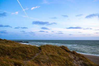 Kum tepeleri arasında Danimarka sahilinden Kuzey Denizi 'ne gün batımı. Yüksek kalite fotoğraf