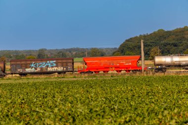 Yük vagonlu kırmızı elektrikli lokomotif arazide ilerliyor. Yüksek kalite fotoğraf