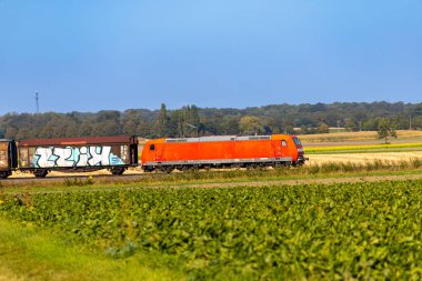 Yük vagonlu kırmızı elektrikli lokomotif arazide ilerliyor. Yüksek kalite fotoğraf