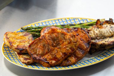 Izgara et, tavuk ve domuz eti ve mavi ve sarı tabakta ızgara yeşil kuşkonmaz. Yüksek kalite fotoğraf