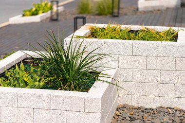 İçi ot dolu doğal taş tuğlalardan yapılmış kaldırılmış yatak, arka planda sokak. Yüksek kalite fotoğraf