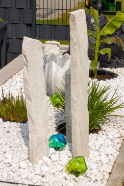 Bir mermer çakıl yatağında üç mermer sütun ve arka planda birkaç bitki. Yüksek kalite fotoğraf