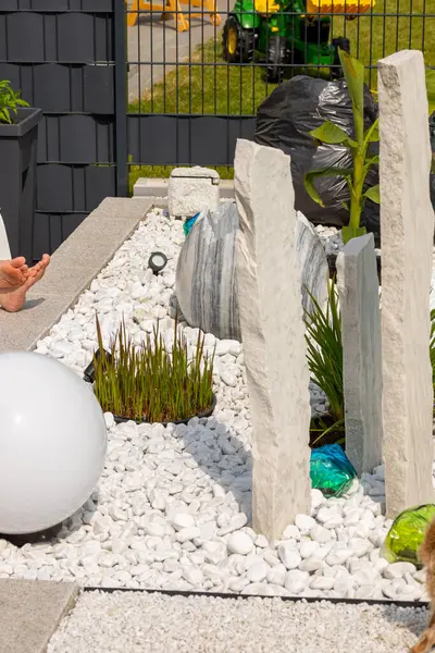 Bir mermer çakıl yatağında üç mermer sütun ve arka planda birkaç bitki. Yüksek kalite fotoğraf