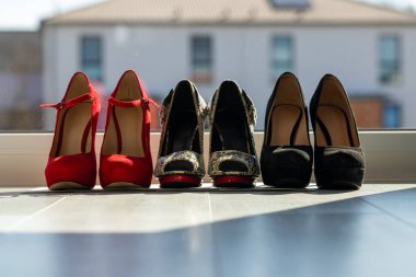 Üç çift kadın ayakkabısı, arka arkaya pencerenin önünde, zeminde. Yüksek kalite fotoğraf