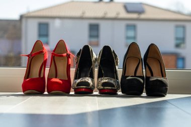 Üç çift kadın ayakkabısı, arka arkaya pencerenin önünde, zeminde. Yüksek kalite fotoğraf