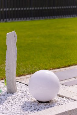 Bir mermer çakıl yatağında üç mermer sütun ve arka planda birkaç bitki. Yüksek kalite fotoğraf