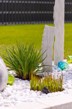 Bir mermer çakıl yatağında üç mermer sütun ve arka planda birkaç bitki. Yüksek kalite fotoğraf