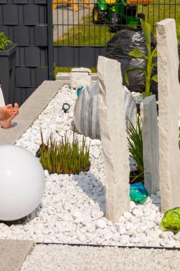 Bir mermer çakıl yatağında üç mermer sütun ve arka planda birkaç bitki. Yüksek kalite fotoğraf