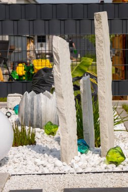 Bir mermer çakıl yatağında üç mermer sütun ve arka planda birkaç bitki. Yüksek kalite fotoğraf