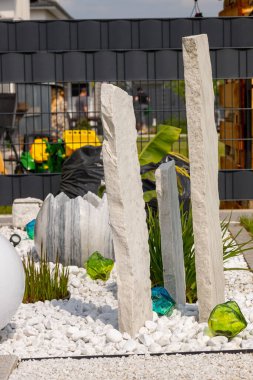 Bir mermer çakıl yatağında üç mermer sütun ve arka planda birkaç bitki. Yüksek kalite fotoğraf