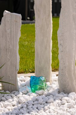 Bir mermer çakıl yatağında üç mermer sütun ve arka planda birkaç bitki. Yüksek kalite fotoğraf