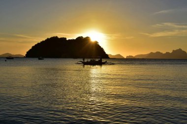 Filipinler 'deki sulara yansıyan parlak sarı ve turuncu gün batımı.
