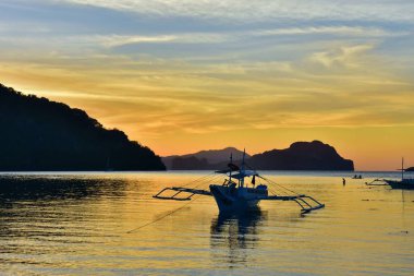 Filipinler 'deki sulara yansıyan parlak sarı ve turuncu gün batımı.