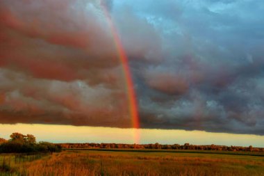 stormy sky with rainbow over the field 