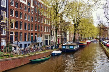 Amsterdam, Hollanda - 7 Nisan 2023: Renkli evlerle çevrili Amsterdam kanallarının güzel manzarası