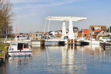 Avrupa, Hollanda, Kuzey Hollanda - 5 Nisan 2023: Hollanda, Kuzey Hollanda 'da bir kanal boyunca asma köprü ve geleneksel Hollanda mimarisi manzarası.