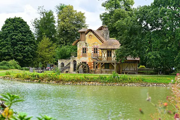 Versailles, Fransa - 18 Haziran 2023: Marie-Antoinette 'nin Versailles Sarayı yakınlarındaki Kraliçe Hamleti' ndeki Değirmen ve gölet.