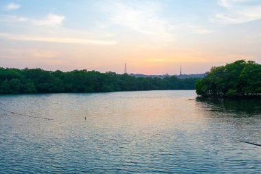 A beautiful sunset with a colorful sky above a river is a sight to behold. The sky is filled with hues of oranges, yellows, pinks, and purples, casting a warm glow over the river.