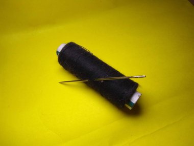 Siyah arka planda sarı iplikli dikiş makinesi.