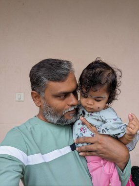 Orta yaşlı beyaz bir baba uyuyan yeni doğmuş bebeği öpüyor. Anne ve baba, sallanan kız evlat oğlunu ellerinde tutuyor. Otantik bir ebeveyn olma anı. Bekar baba aile hayatı..