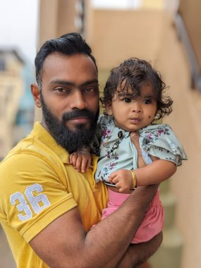 Mutlu, gülümseyen bir amca yeğeniyle vakit geçirir, bebeği omzuna alır ve ona nazikçe destek olur. Bebek gülümser ve parmağını tutar.