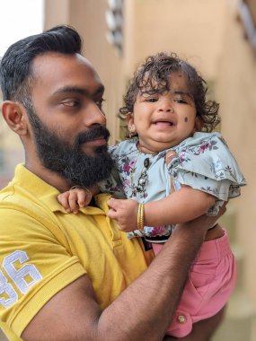 Mutlu, gülümseyen bir amca yeğeniyle vakit geçirir, bebeği omzuna alır ve ona nazikçe destek olur. Bebek gülümser ve parmağını tutar.