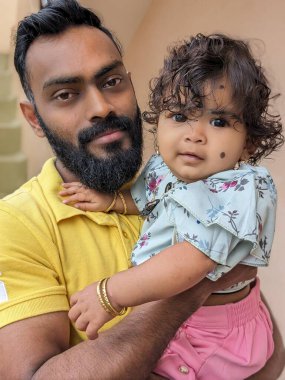 Mutlu, gülümseyen bir amca yeğeniyle vakit geçirir, bebeği omzuna alır ve ona nazikçe destek olur. Bebek gülümser ve parmağını tutar.