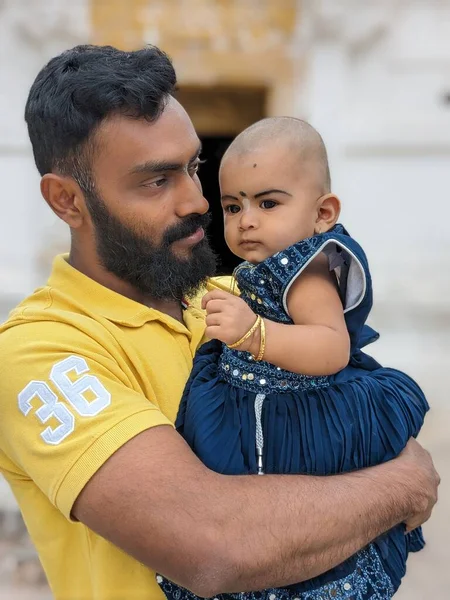 Mutlu, gülümseyen bir amca yeğeniyle vakit geçirir, bebeği omzuna alır ve ona nazikçe destek olur. Bebek gülümser ve parmağını tutar.