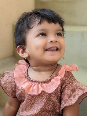 Gülümseyen kız portresi basamaklarda oturuyor, sevimli bir ifadeyle geleneksel yeşil bilezikler takıyor. 