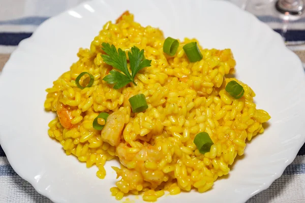 Classic shrimp risotto with arborio rice and saffron, garnished with fresh parsley and chives