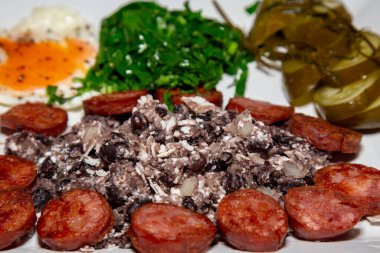 Geleneksel Brezilya yemeği, fasulye, sosis, yumurta, lahana ve mayalanmış salatalık.