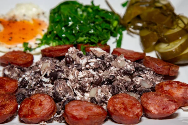 Geleneksel Brezilya yemeği, fasulye, sosis, yumurta, lahana ve mayalanmış salatalık.