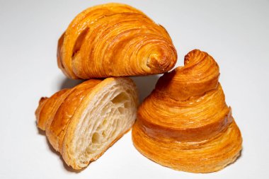 Sade arka planda gölgesi olan altın rengi tereyağlı kruvasan..