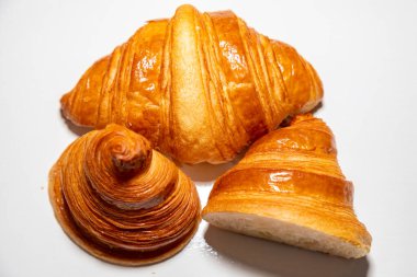 Sade arka planda gölgesi olan altın rengi tereyağlı kruvasan..