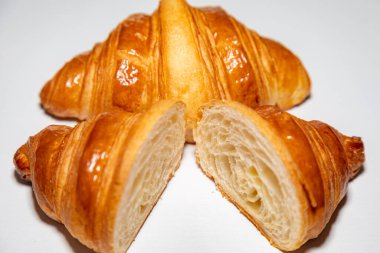 Sade arka planda gölgesi olan altın rengi tereyağlı kruvasan..