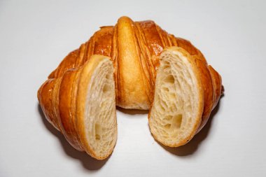 Sade arka planda gölgesi olan altın rengi tereyağlı kruvasan..