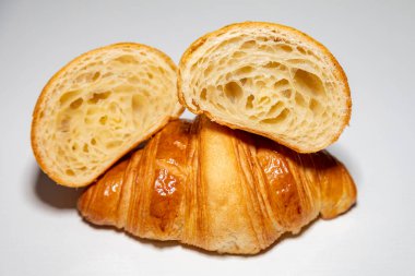 Sade arka planda gölgesi olan altın rengi tereyağlı kruvasan..