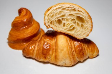 Sade arka planda gölgesi olan altın rengi tereyağlı kruvasan..