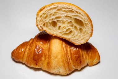 Sade arka planda gölgesi olan altın rengi tereyağlı kruvasan..