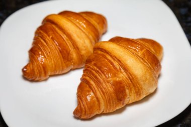 Sade arka planda gölgesi olan altın rengi tereyağlı kruvasan..