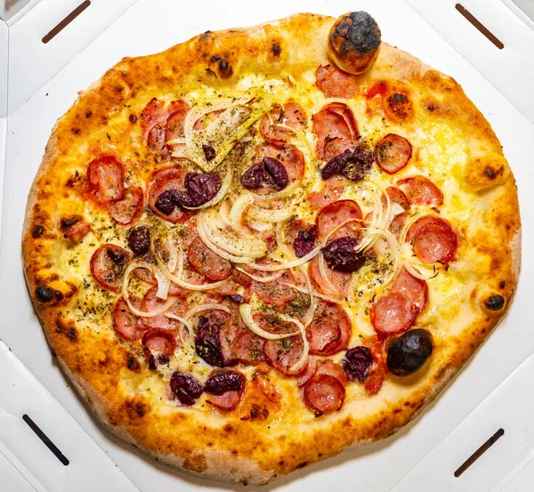 stock image Traditional rustic pizza with pepperoni, black olives, onion and basil