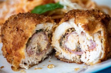 Geleneksel tavuk Kiev, ekmekli, doldurulmuş ve kızartılmış domates soslu spagetti ve rendelenmiş parmesan peyniri ile servis ediliyor.