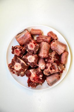 Yuvarlak beyaz tabakta çiğ sığır kuyruğu..