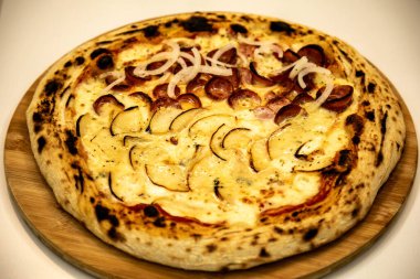 Gorgonzola ve peynirli yarım armut ve soğanlı yarım biberli pizza.