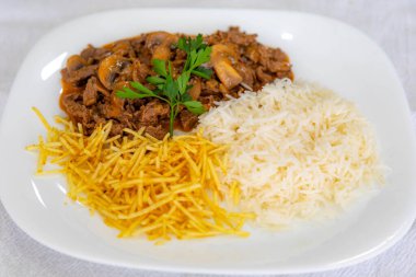 Geleneksel fileminyon mantarlı stroganoff, patates kızartması ve pilav.