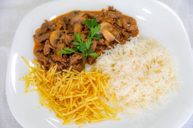 Geleneksel fileminyon mantarlı stroganoff, patates kızartması ve pilav.