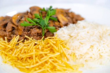 Geleneksel fileminyon mantarlı stroganoff, patates kızartması ve pilav.