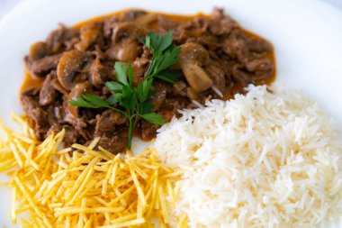 Geleneksel fileminyon mantarlı stroganoff, patates kızartması ve pilav.